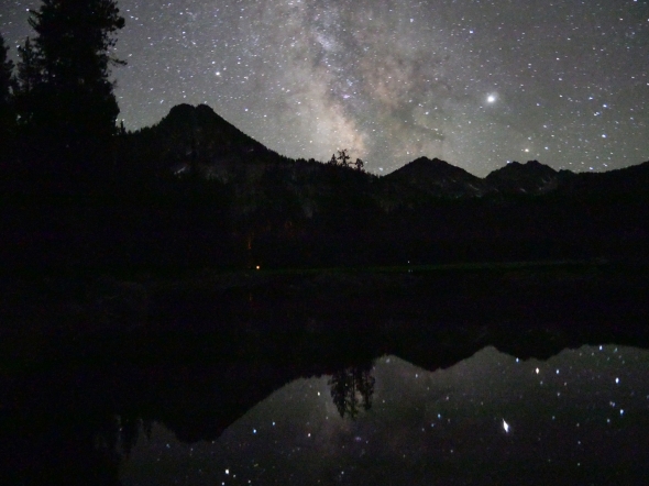 Stars in night sky, mountains and reflections in like