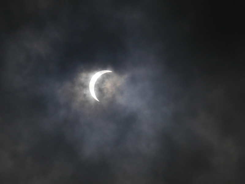 crescent sun and clouds during solar eclipse